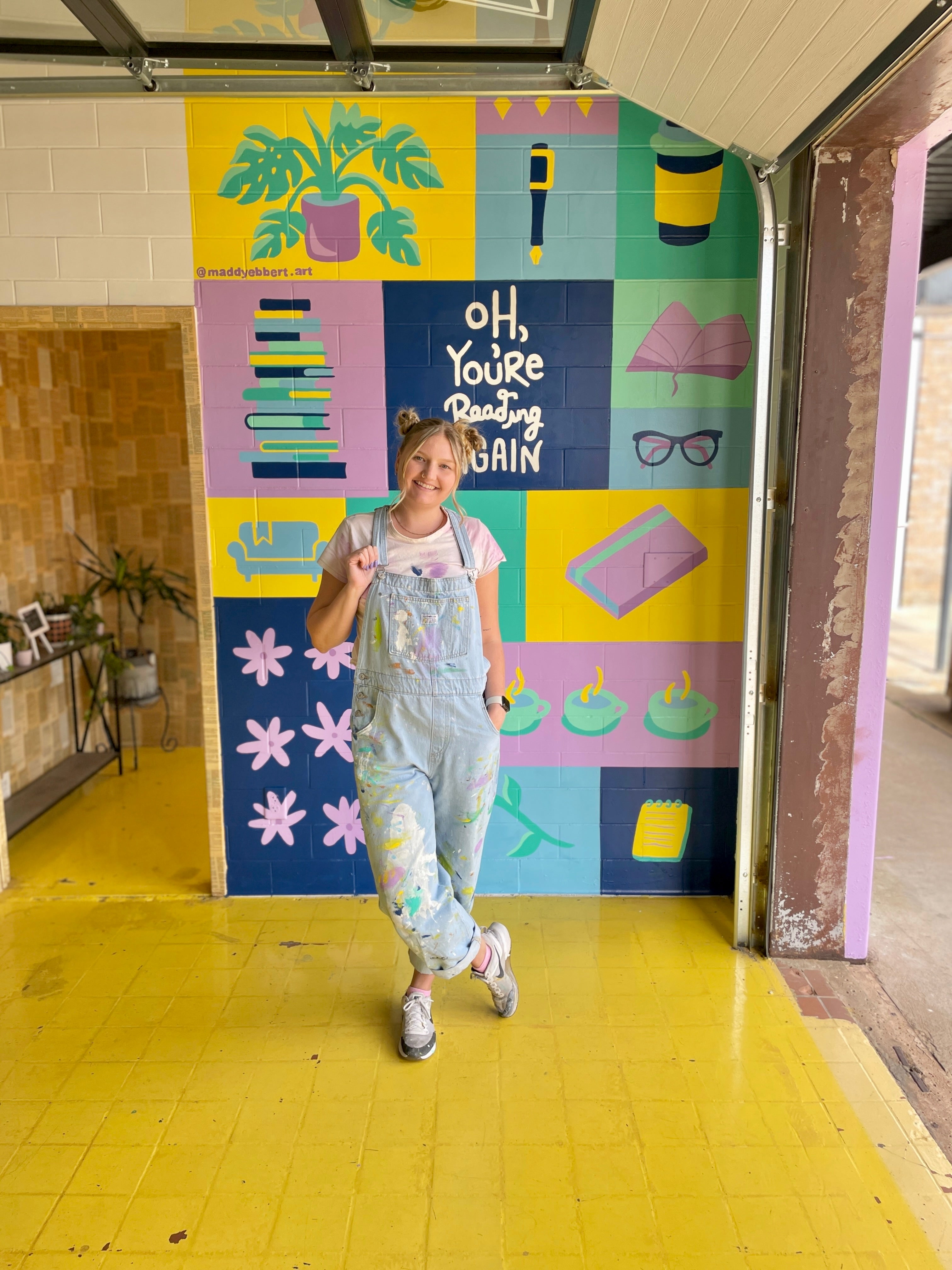 Book store mural books purple bigtails paint artist art overalls person blonde cute art wall mural brick inside shop